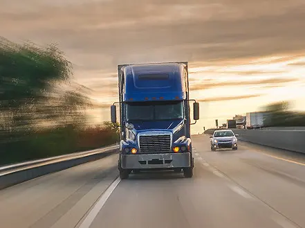 A blue semi truck driving on a highway